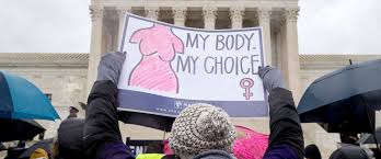 A scene of women at the bottom of the Supreme Court in protest carrying signs stating my body, my choice.